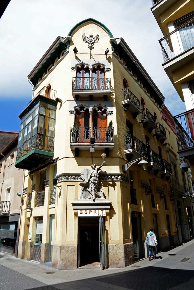 Olot.- Casa Gassiot, d'estil modernista del S. XX amb tres façanes. La central té una figura al·legòrica i dos pisos amb balcons (5/2017)