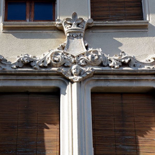 Olot.- Casa Masllorens d'estil modernista del S. XIX. Detall de la part superior de la motllura decorada amb motius vegetals i un cap (4/2017)