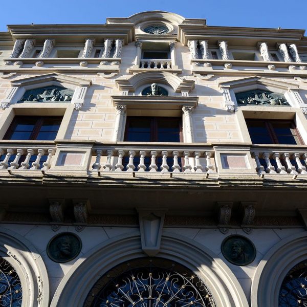 Olot.- Teatre Principal. Vista del balcó del segon pis amb balustrada de pedra i finestres del tercer pis amb columnes de motius vegetals (3/2017)