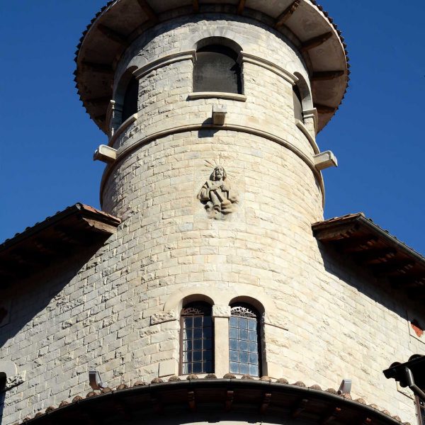 Olot.- Casa Pujadors, d'estil modernista-historicista del S. XX. Torre circular amb la coberta cònica i el relleu del Sant Crist al frontal (12/2016)