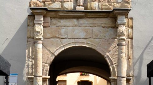 Olot.- Porta renaixentista de la façana de l'antic hospital de Sant Jaume d'arc de mig punt flanquejat per columnes i al damunt té l'imatge del Sant (6/2017)