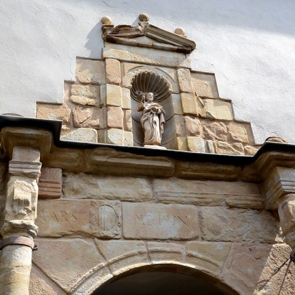 Olot.- Porta renaixentista de la façana de l'antic hospital de Sant Jaume d'arc de mig punt flanquejat per columnes i al damunt té la imatge del Sant (6/2017)