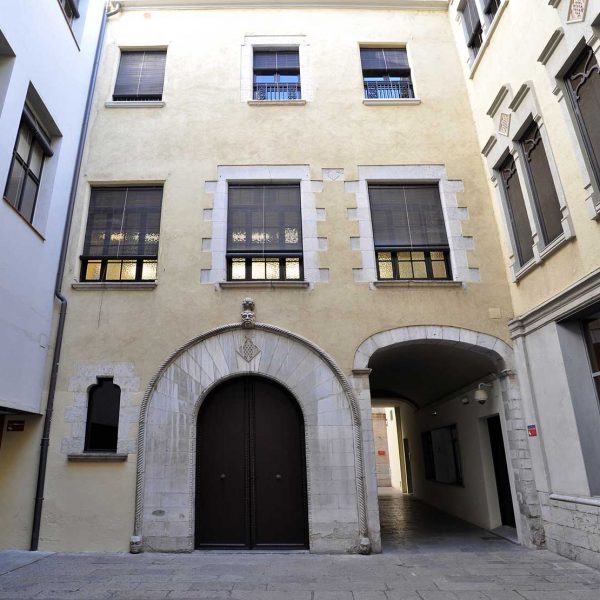 Girona.- Ajuntament, d'estil eclecticisme. Porta adovellada del pati interior amb l'escut de la ciutat. A sobre hi ha esculpida una cara (11/2013)