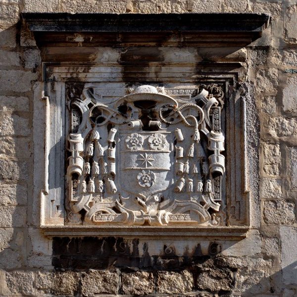 Girona.- Palau Episcopal, d'estil romànic/gòtic que alberga el Museu d'Art de Girona. Làpida de la façana amb l'escut episcopal renaixentista (11/2013)