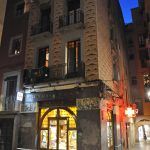 Girona.- Farmàcia Plana, situada a l a planta baixa d'un edifici noucentista. Te dues grans portes als angles i un fris de plafons ceràmics (11/2013)