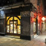 Girona.- Farmàcia Plana, situada a l a planta baixa d'un edifici noucentista. Te dues grans portes als angles i un fris de plafons ceràmics (11/2013)