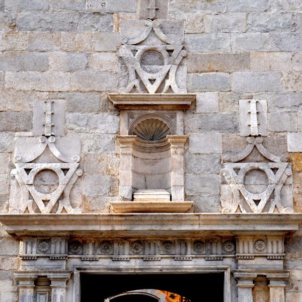 Girona.- Hospital de Santa Caterina. Sobre l'arquitrau de la porta hi figura una fornícula buida i ornaments geomètrics (5/2014)