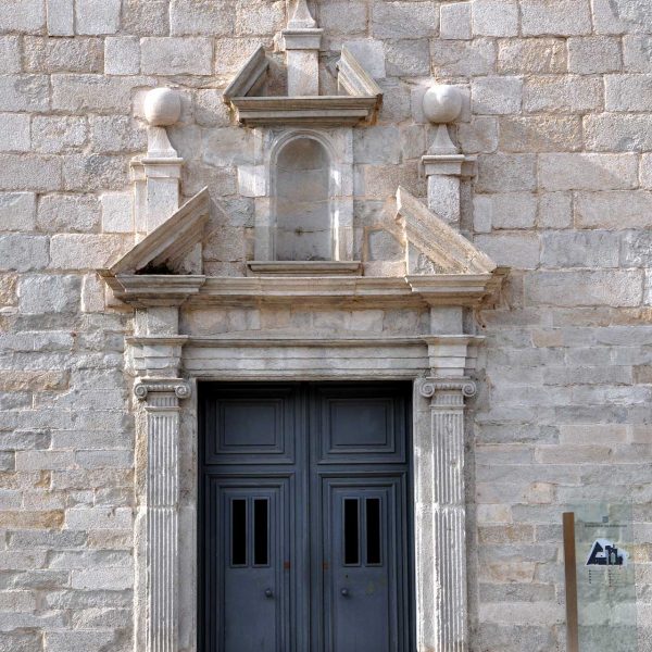 Girona.- Porta de l'antiga capella de l'hospital de Santa Caterina emmarcada per falses columnes, sobre el dentell hi ha una fornícula buida (5/2014)