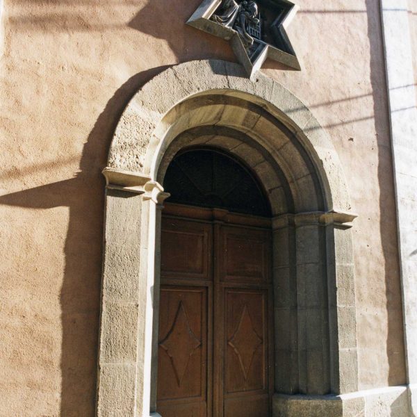 Vic.-Església de Sta. Caterina (1890).Porta d'arc de mig punt amb un medalló polièdric on figura la Verge del Roser mostrant l'infant Jesús a Sta. Caterina (8/2000)
