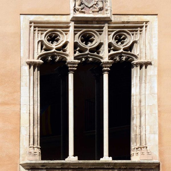 Vic.- Llotja del Blat. Finestral gòtic triforat de la façana de llevant amb calats suportat per dues columnes de marbre i al damunt l’escut de la ciutat (7/2018)