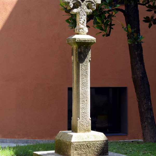 Vic.- Hospital de la Santa Creu, S. XIV. Creu de pedra erigida al centre del pati renaixentista del S. XVI formada per quatre cilindres oberts per un cantó (7/2018)