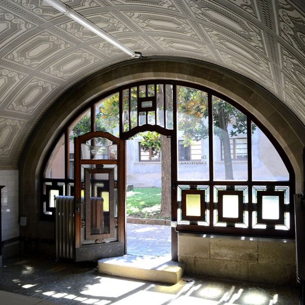 Vic.- Hospital de la Santa Creu, S. XIV. Farmàcia del 1932-33 de Josep Maria Pericas. Gran portalada i coberta pintada amb esgrafiats geomètrics (7/2018)