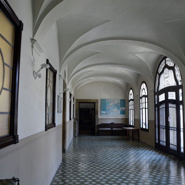 Vic.- Hospital de la Santa Creu, S. XIV. Corredor amb finestres i porta d’accés a la escala del pati (7/2018)