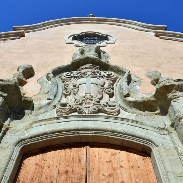 Vic.- Església barroca de la Santa Creu, S. XVIII. La porta de la façana està flanquejada per pilastres rematades amb florons i un escut al timpà (6/2020)