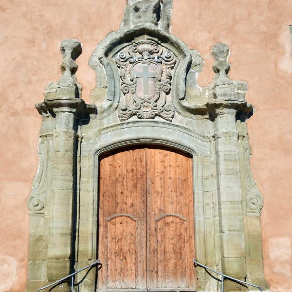 Vic.- Església barroca de la Santa Creu, S. XVIII. La porta de la façana està flanquejada per pilastres rematades amb florons i un escut al timpà (6/2020)