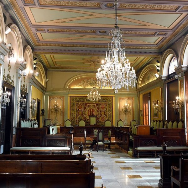 Lleida.- Casa de la Vila, S. XIII/XIX. Sala de sessions rectangular amb el cadirat en forma de U invertida adornada amb tapissos i làmpades de cristall (9/2020)