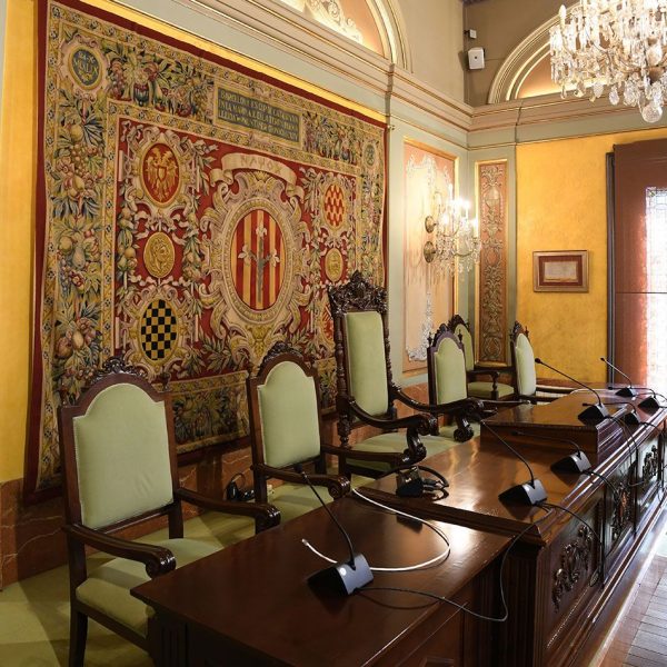 Lleida.- Casa de la Vila, S. XIII/XIX. Sala de sessions rectangular amb el cadirat en forma de U invertida adornada amb tapissos i làmpades de cristall (9/2020)
