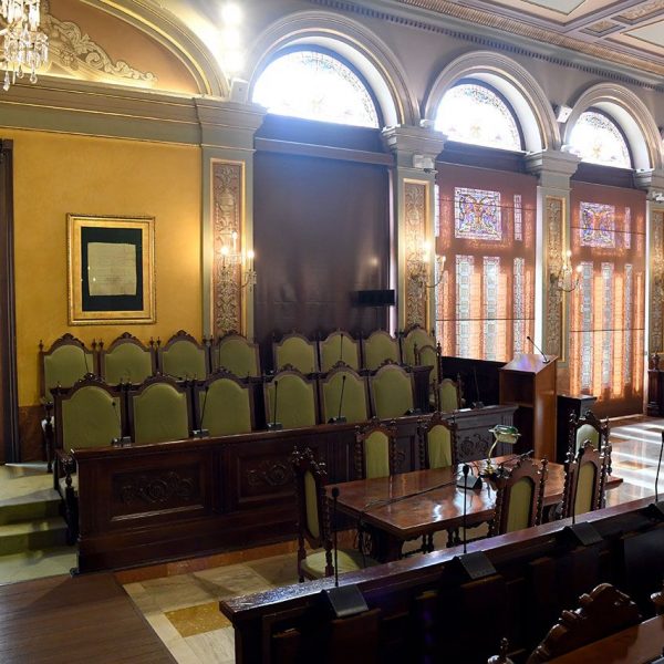 Lleida.- Casa de la Vila, S. XIII/XIX. Sala de sessions rectangular amb el cadirat en forma de U invertida adornada amb tapissos i làmpades de cristall (9/2020)