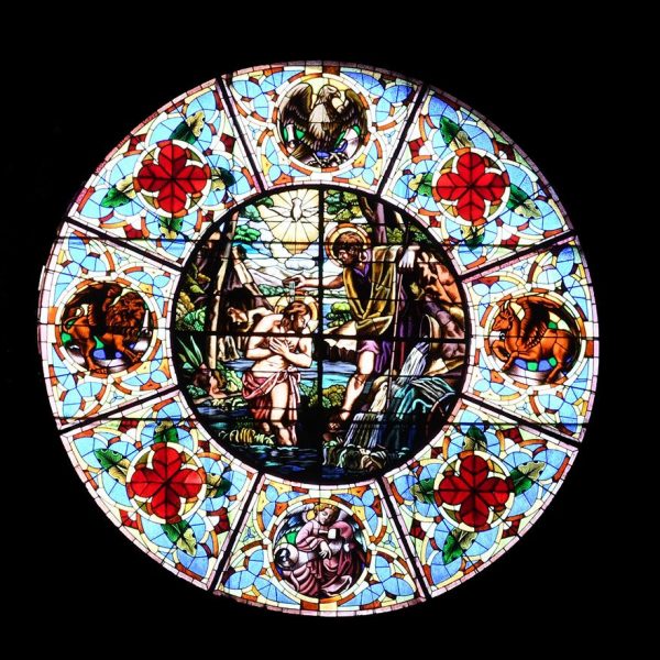 Lleida.- Església neogòtica de Sant Joan, S. XIX. Rosassa de vitralls de colors amb l'escena del baptisme de Jesús i dels quatre evangelistes (9/2020)