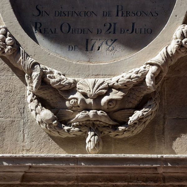 Lleida.- Font del Roser, neoclàssica de l'any 1830. Decoració grotesca sota la orla commemorativa de la construcció de la font (9/2018)