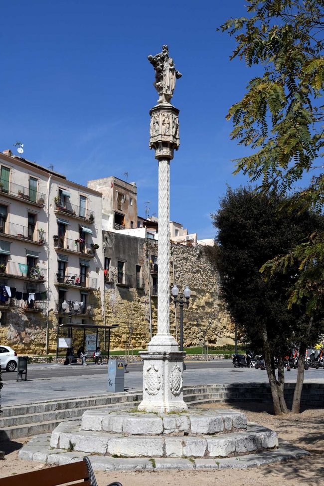 Tarragona.-Creu de terme del S. XVII del portal de S. Antoni sobre un peu quadrat datat de 1604. La magolla es vuitavada amb imatges de sants (3/2021)