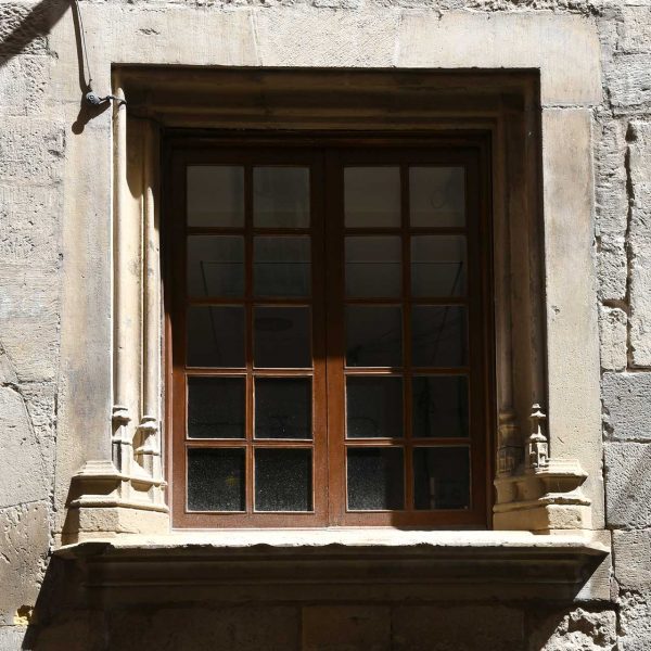 Tortosa.- Palau Oriol, gòtic del S. XV – Finestra quadrada de l’entresol amb llinda moderna i columnetes laterals esculpides amb culs de llàntia (7/2022)