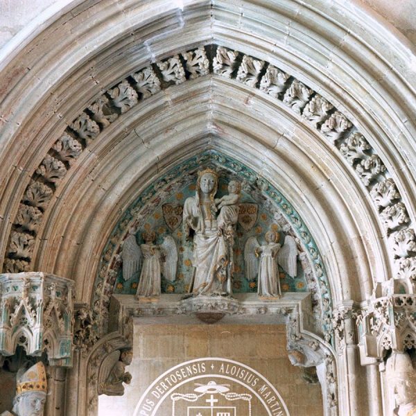 Tortosa.- Palau Episcopal – Porta de la capella d’arc apuntat amb un magnífic treball escultòric on trobem la Verge i el nen entre dos àngels en el timpà (2/2003)
