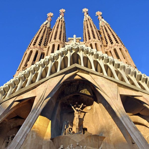 Barcelona.- Sagrada Família – Façana de la Passió que consta de tres portals, quatre torres i un porxo de sis columnes inclinades acabades amb una cornisa que sosté un cimari (11/2023)