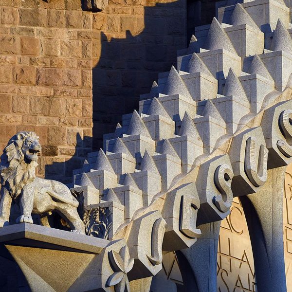 Barcelona.- Sagrada Família – Façana de la Passió – Cimari sostingut per divuit columnes on hi ha l’escultura del lleó de Judà dalt una peanya a l’inici del text (11/2023)