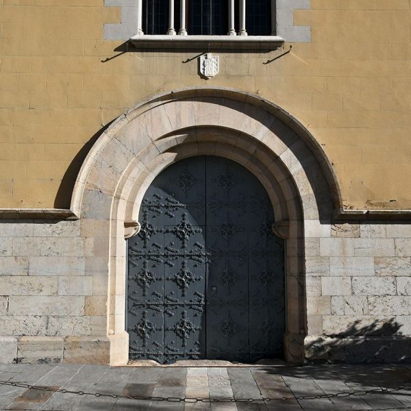 La Seu d’Urgell.- Palau Episcopal refet en el S. XIX – Porta oberta a la façana de ponent adovellada d’arc de mig punt amb arquivoltes envoltada d’una motllura (2/2025)