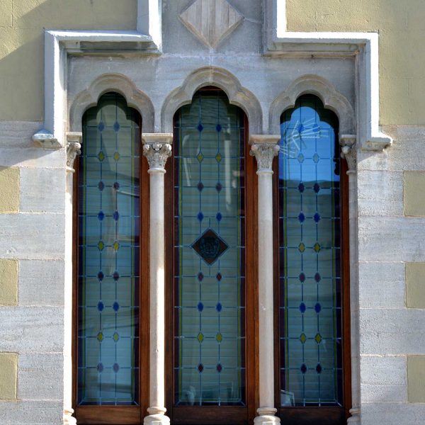 La Seu d’Urgell.- Palau Episcopal refet en el S. XIX – Finestra gòtica lateral triforada i trilobulada suportada per dues columnetes amb capitells esculpits (11/2015)