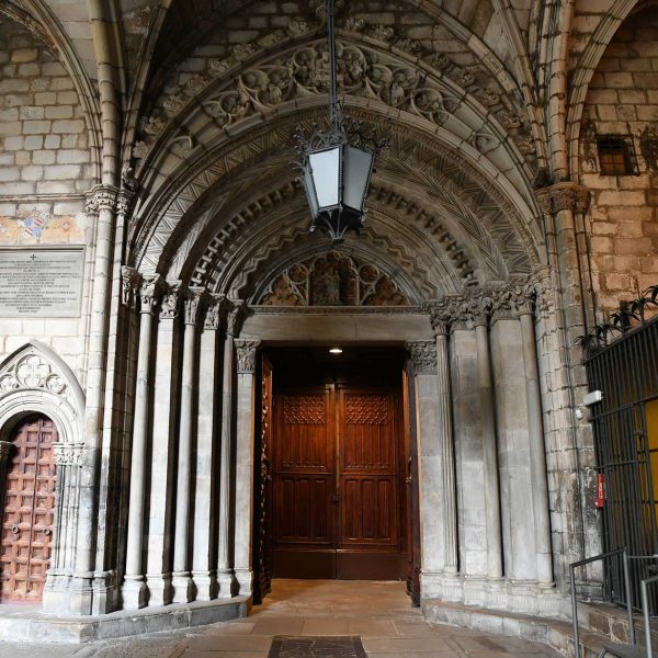 Barcelona.- Catedral de la Santa Creu i Santa Eulàlia – Porta d’accés al claustre des de l’església d’arquivoltes en degradació. Pel damunt té afegida una arcada amb cresteria (1/2026)