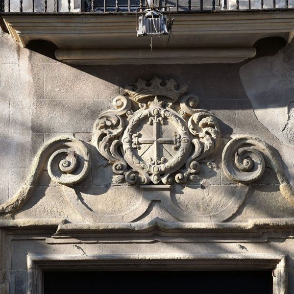 Vic.- Convent de Sant Domènec, S. XVII - Entaulament de la porta del claustre format per volutes amb un escut central en forma de creu encerclada (6/2020)