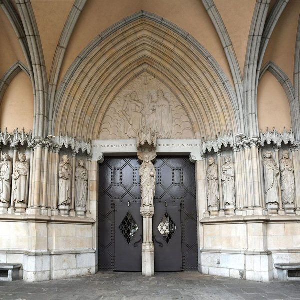 Terrassa.- Catedral del Sant Esperit del 1574 – Atri amb la porta principal dividida per un mainell amb la imatge de Crist i al timpà la Santíssima Trinitat de Carles Armiño (1/2026)