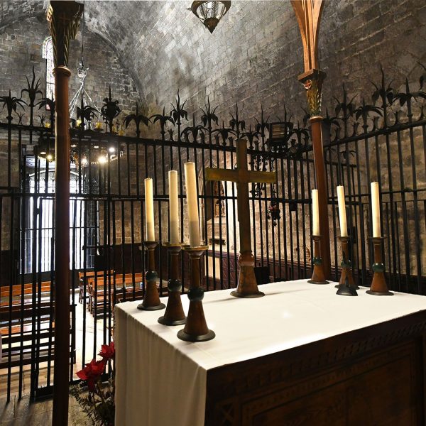 Barcelona.- Capella romànica de Santa Llúcia construïda entre 1557 i 1268 – Vista del fons de la nau amb l’altar sobre aixecat a través de dos esglaons protegit per una reixa de forja (3/2026)