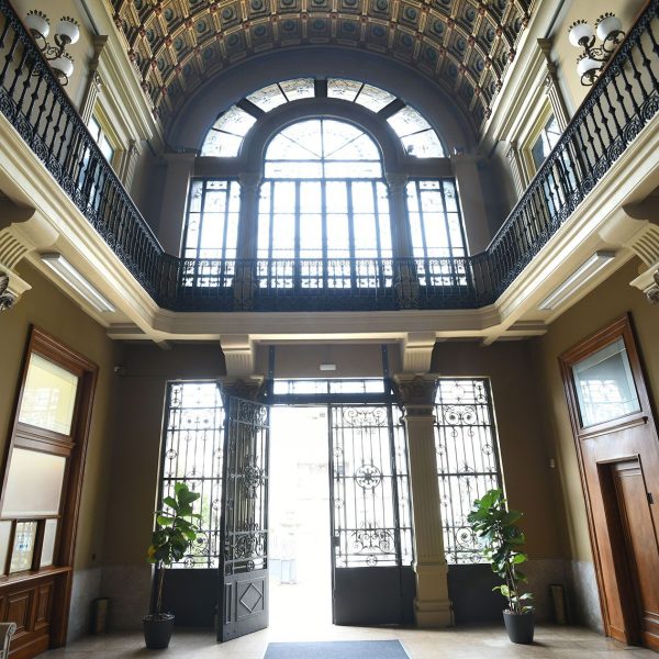 Terrassa.- Magatzems Pasqual Sala (1893) - Interior del vestíbul de doble alçada cobert amb volta de canó de cassetons il·luminat a través de la portalada i el balcó del pis (1/2026)