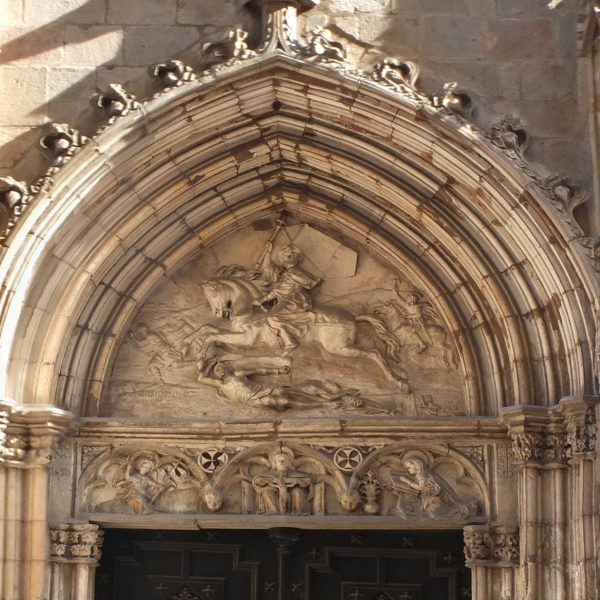 Barcelona.- Església de Sant Jaume reformada en el S. XIX – Llinda on hi ha representada l’Anunciació i la Trinitat i el timpà amb Sant Jaume del 1878 obra de Josep Santigosa (3/2026)