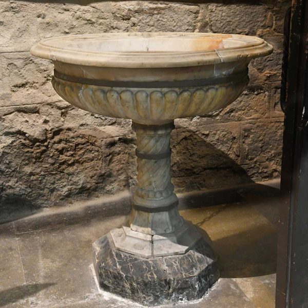Barcelona.- Església de Sant Jaume – Pica baptismal/beneitera de marbre de boca circular motllurada envoltada de gallons sobre un fust helicoïdal i peu flexionat octogonal (3/2026)
