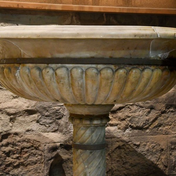 Barcelona.- Església de Sant Jaume – Pica baptismal/beneitera de marbre de boca circular motllurada envoltada de gallons sobre un fust helicoïdal i peu flexionat octogonal (3/2026)