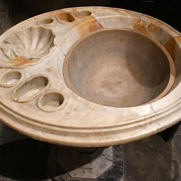 Barcelona.- Església de Sant Jaume – Pica baptismal/beneitera de marbre de boca circular motllurada on hi ha buidats diversos recipients per la pràctica del baptisme (3/2026)