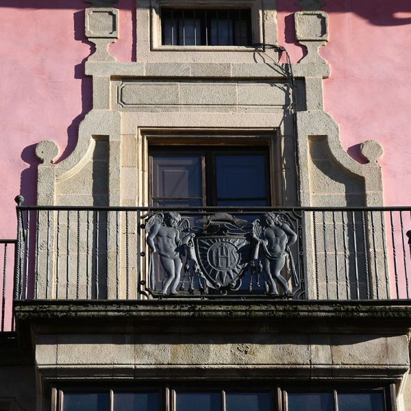 Vic.- Palau Episcopal projectat l’any 1671 de Fra Josep de la Concepció – Balcó sobre la tribuna de la porta principal de l’any 1915 decorada amb el monograma de Jesús (1/2026)