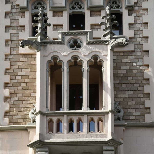 Vic.- Casa Comella, S. XIX d’estil modernista – Tribuna triforada del cos central acabat amb pinacles florals i gàrgoles zoomorfes alades (7/2026)