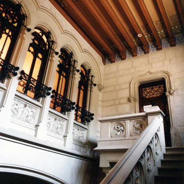 Vic.- Casa Comella, S. XIX d’estil modernista - Escala noble interior d'accés al primer pis amb una galeria de cinc finestrals amb reixes de forja i sostre enteixinat (9/2000)