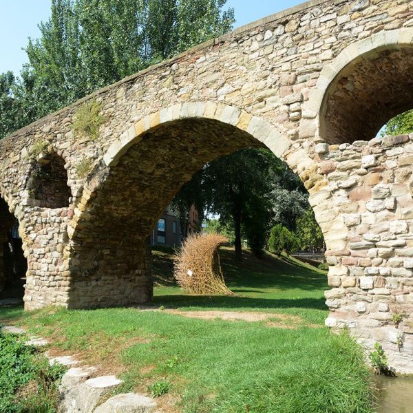 Vic.- Pont romànic de Queralt, S. XI sobre el riu Meder molt modificat i conserva quatre dels set arcs originaris. Disposa de tallamars i a les pilastres hi han oberts sobreeixidors (8/2018)