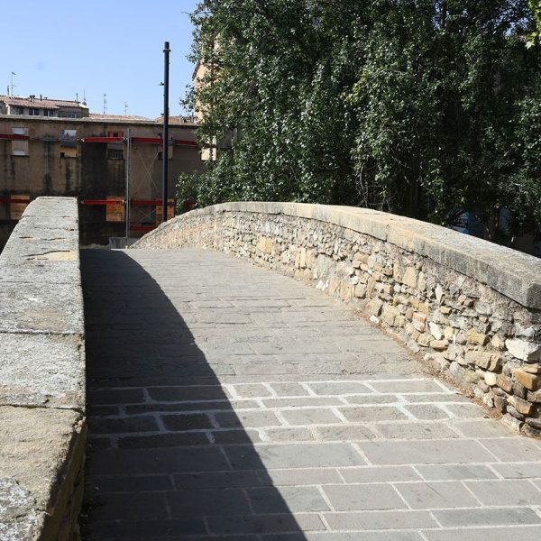Vic.- Pont romànic de Queralt, S. XI sobre el riu Meder molt modificat – Calçada recta amb un desnivell poc pronunciat protegit per baranes de pedra i paviment modern (4/2026)