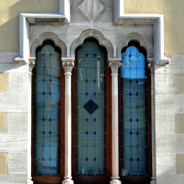 La Seu d’Urgell.- Palau Episcopal refet en el S. XIX – Finestra gòtica lateral triforada i trilobulada suportada per dues columnetes amb capitells esculpits (11/2015)